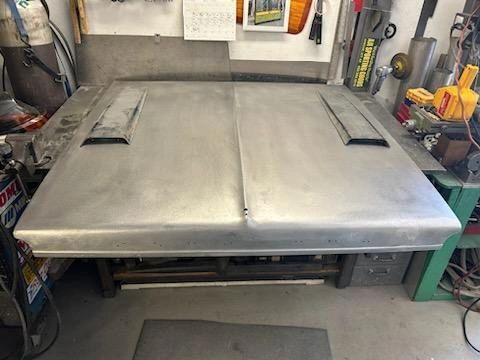 Metal car hood on workshop table.
