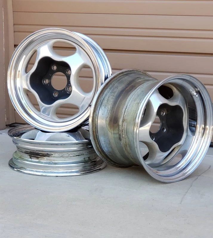 Four stacked silver car wheel rims.
