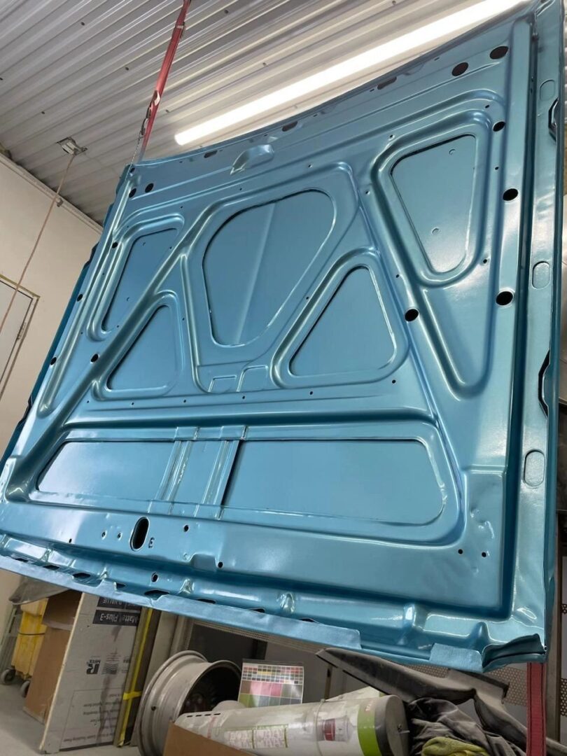 Blue car hood hanging in garage.