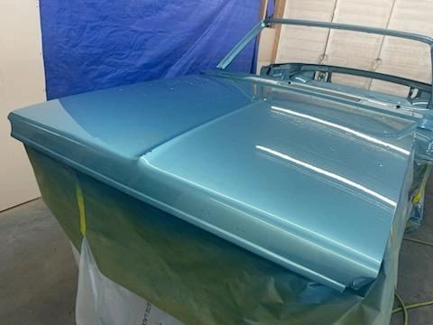 Blue car hood in a workshop setting.