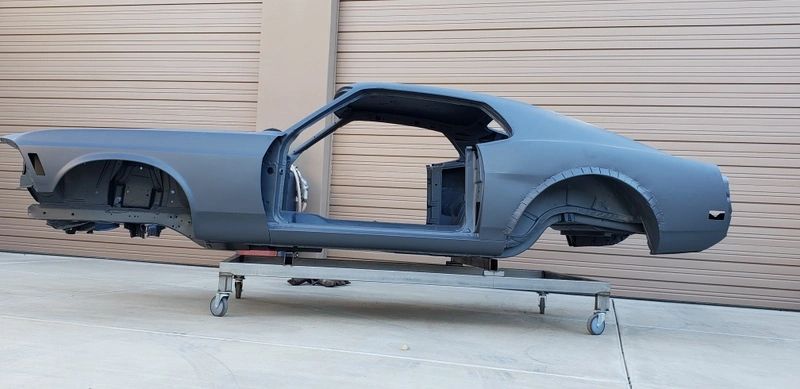 Gray car chassis on wheeled platform.