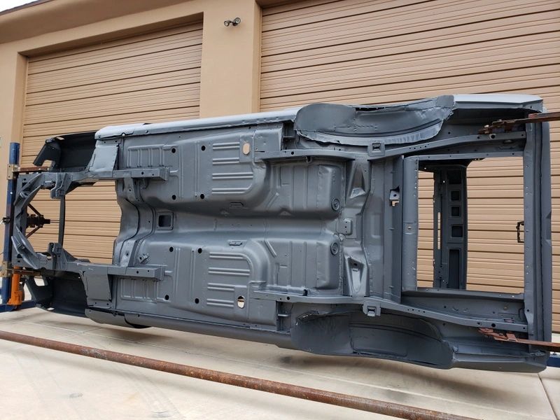 Car chassis on its side outside garage.