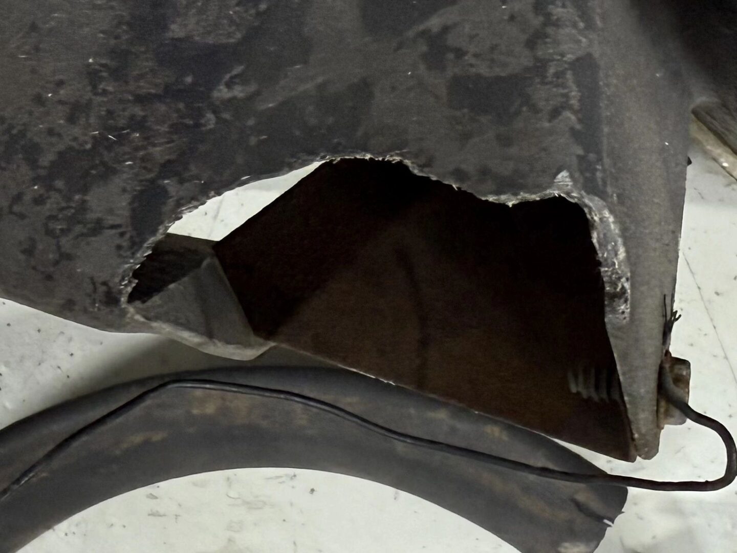 Damaged metal part with exposed interior section.