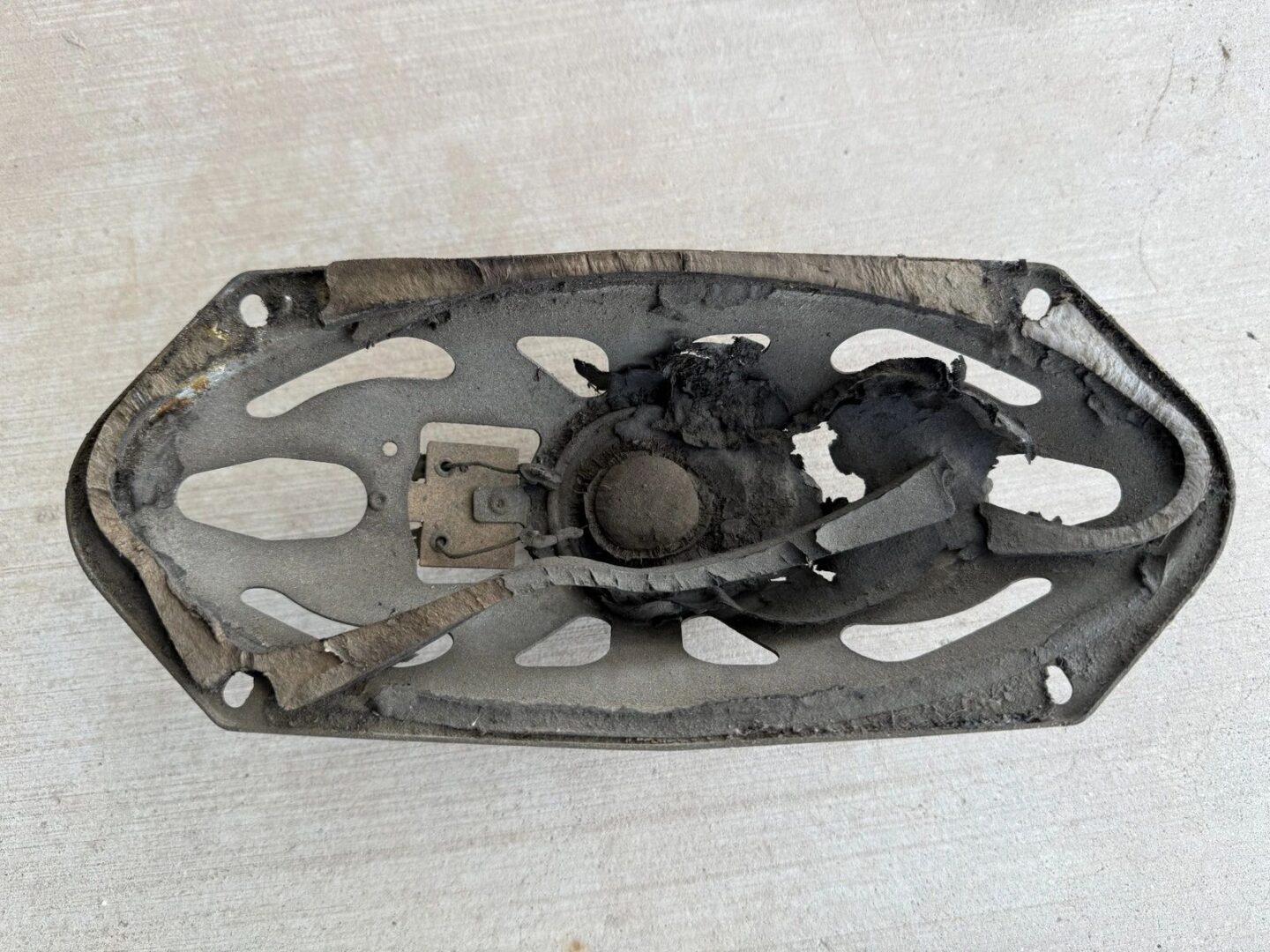 Damaged, burnt speaker on a white surface.