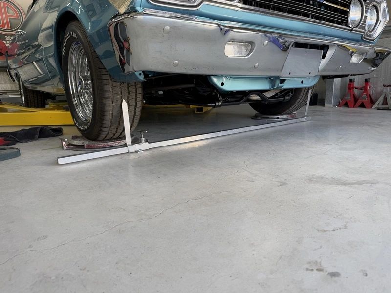 Classic car on lift with alignment tools.