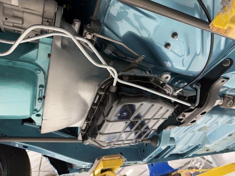 Car underside showing mechanical components and wiring.