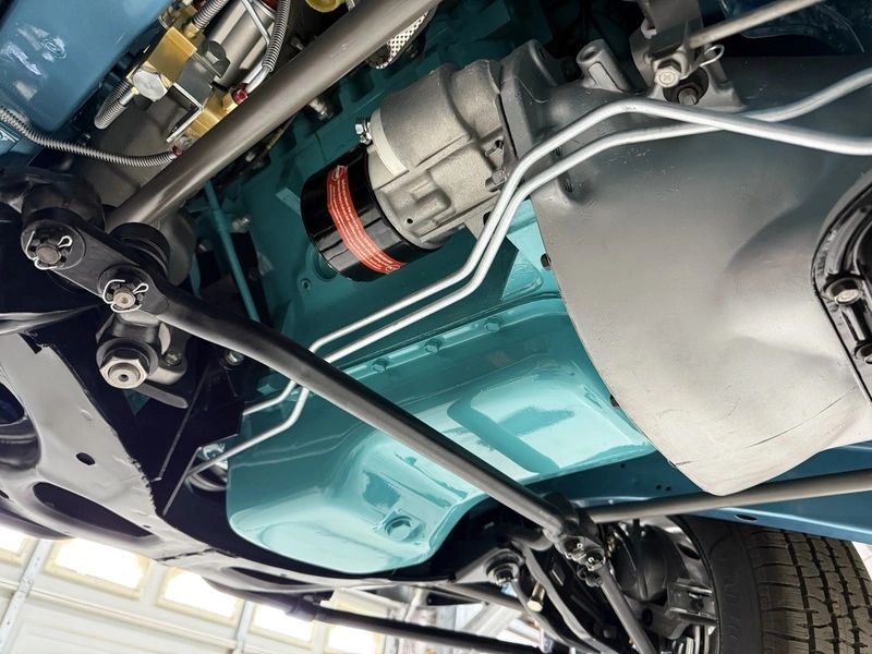Classic car undercarriage with visible transmission components.