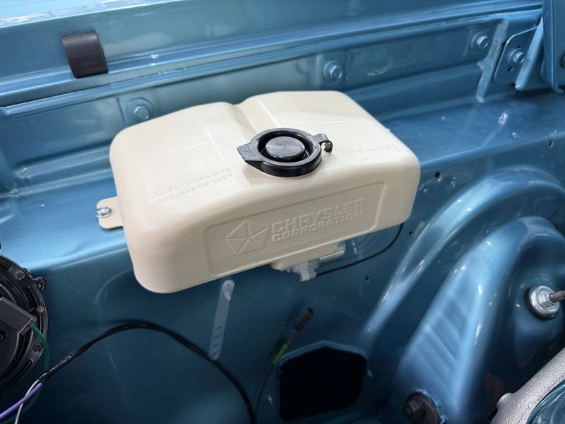Engine bay with Chrysler coolant reservoir.