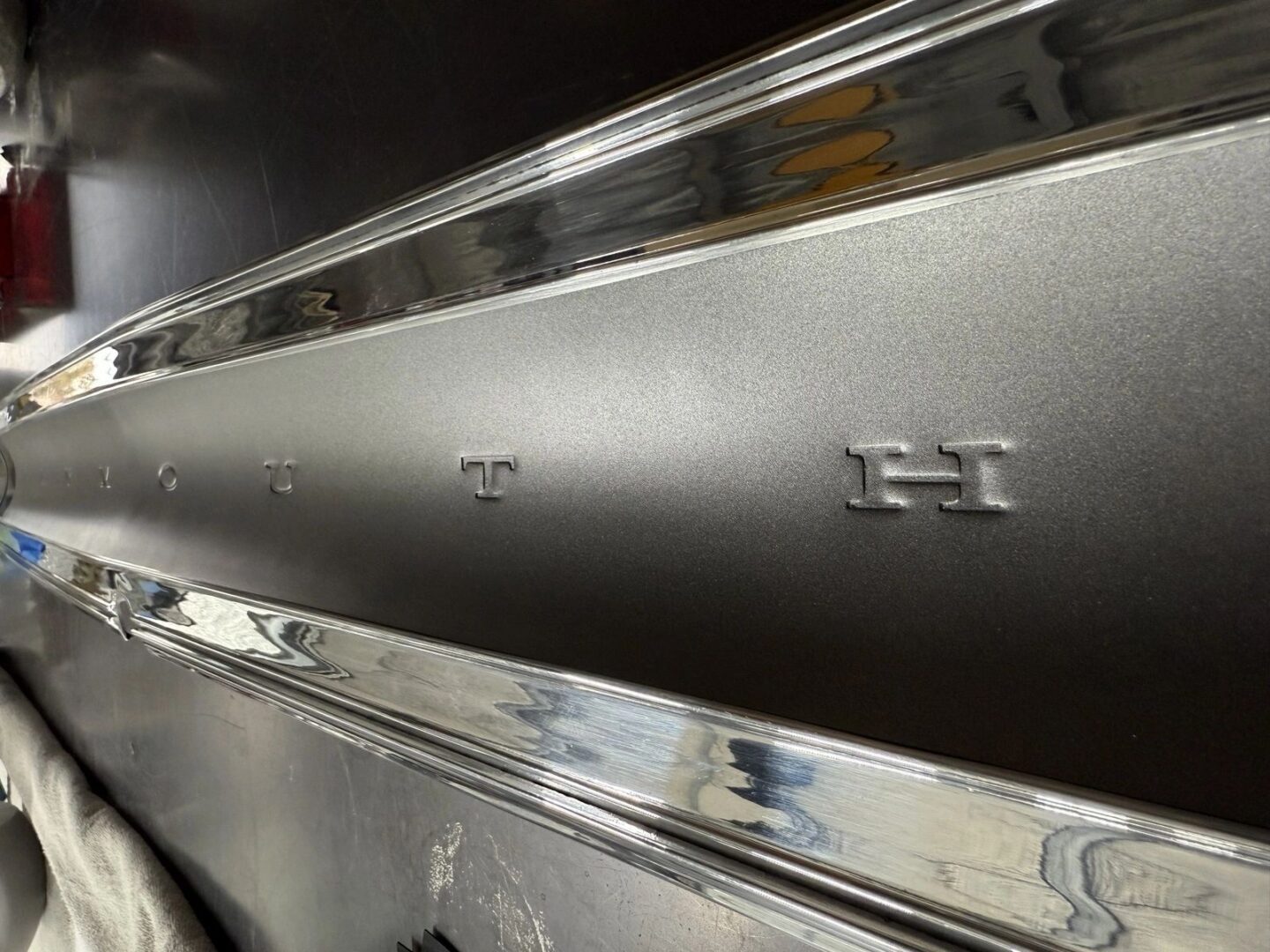 Chrome car emblem with embossed letters.