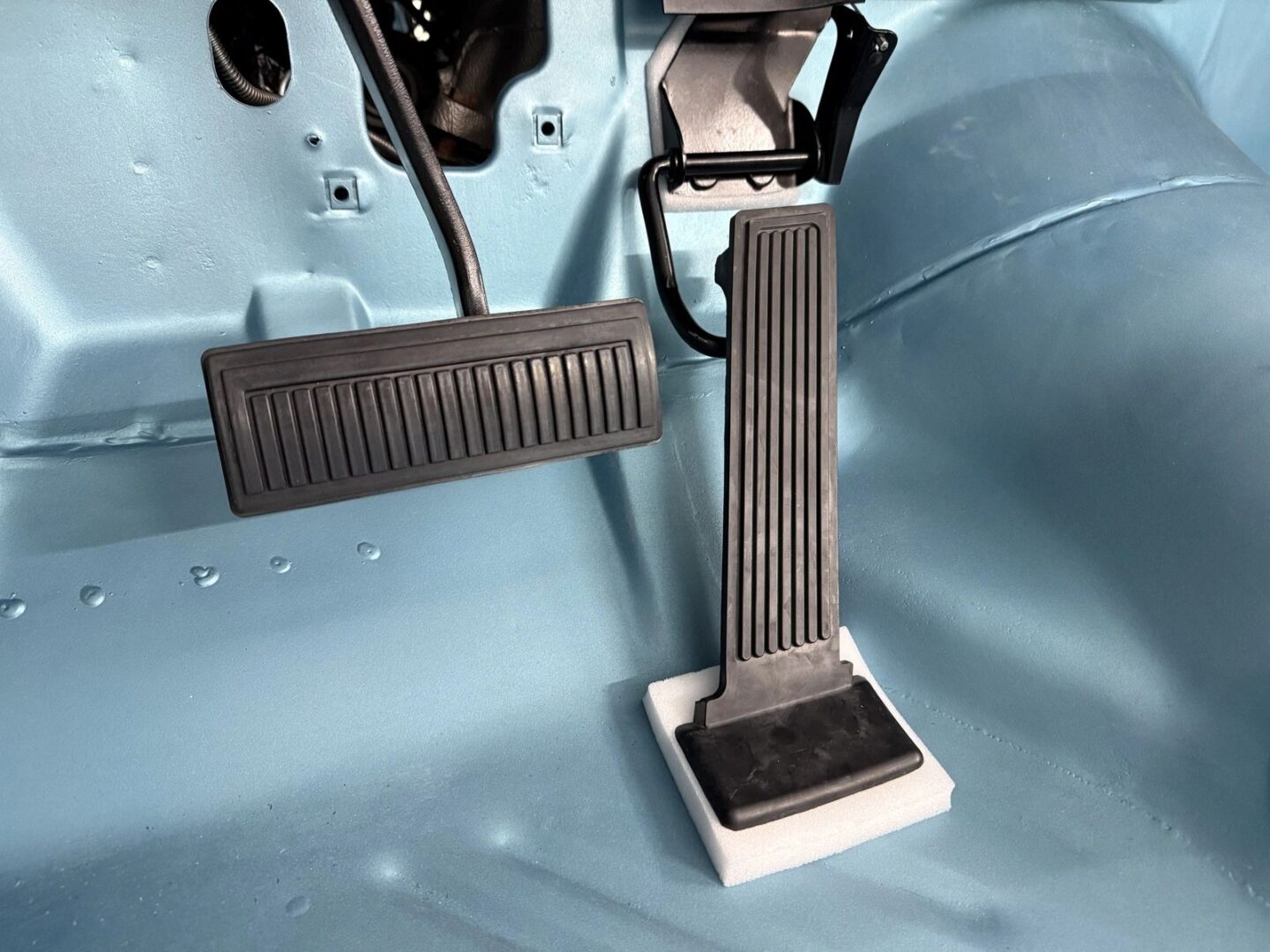 Car pedals on a blue vehicle floor.