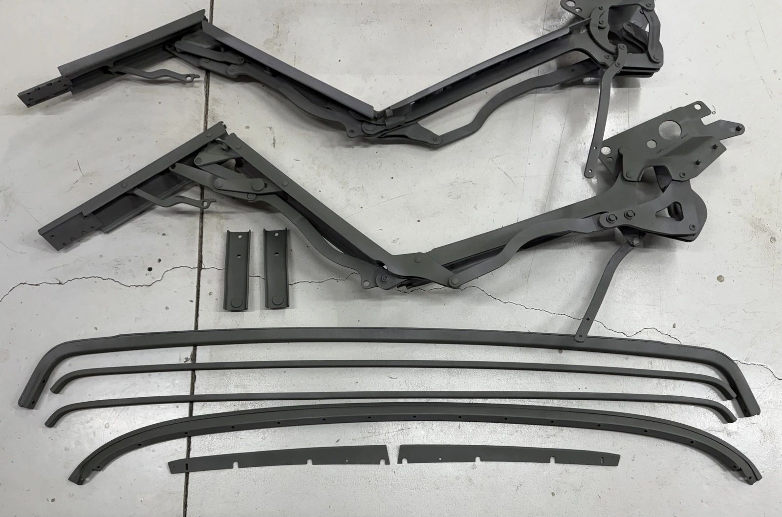 Convertible car top frame parts on floor.