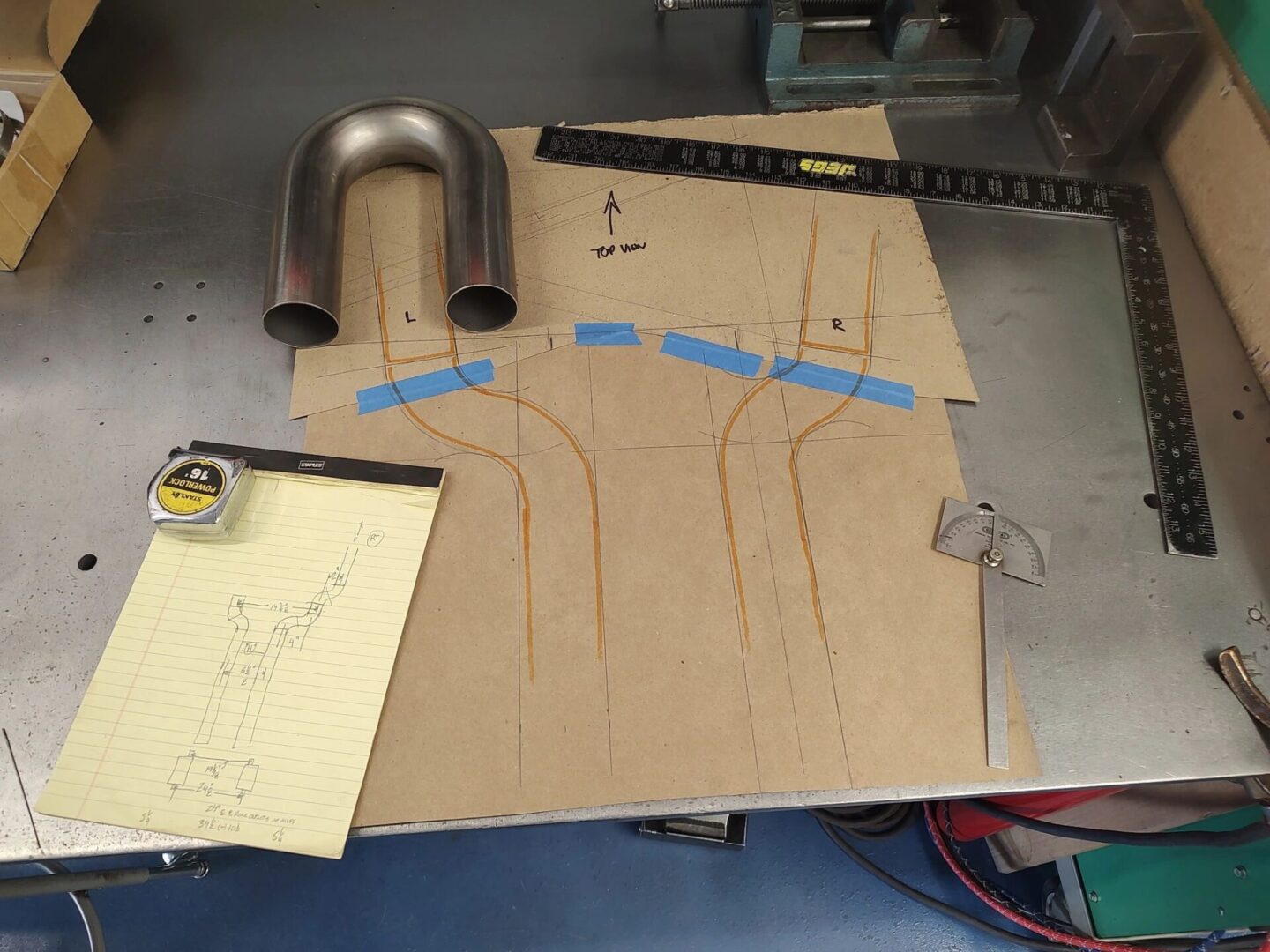 Metalwork plans with tools on workbench.