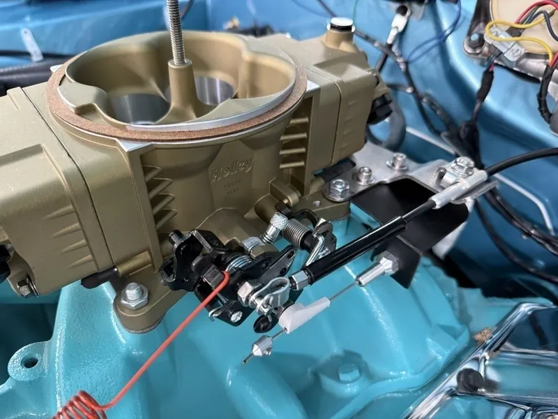 Carburetor on blue engine with cables attached.