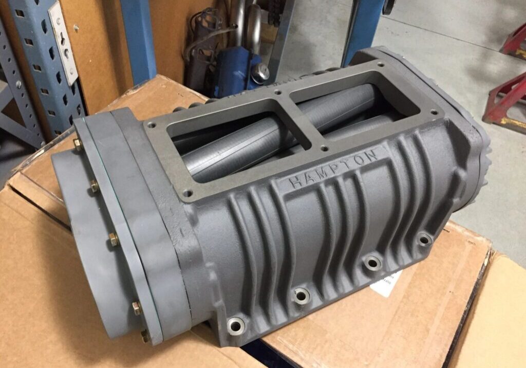 Supercharger on cardboard box in workshop.