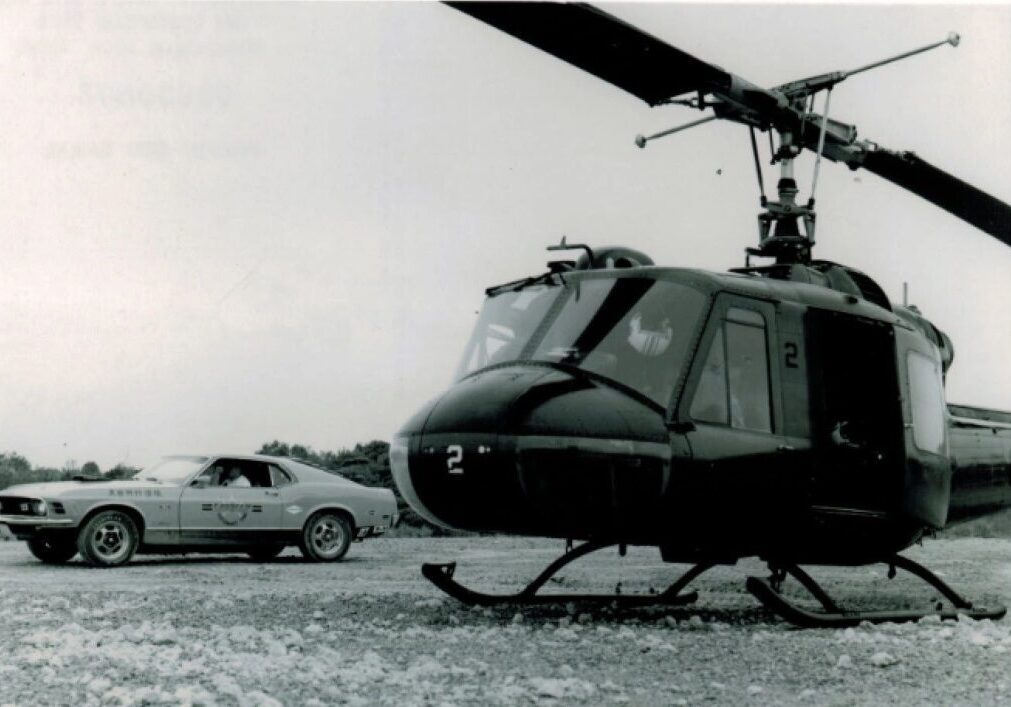Helicopter and car parked on rocky ground.