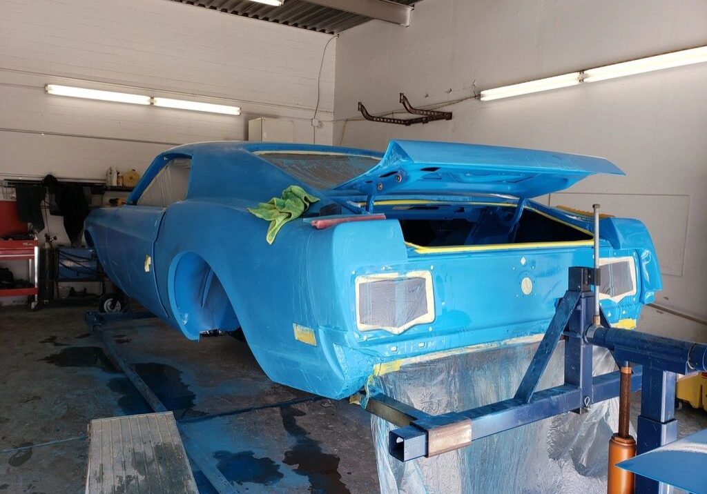 Blue vintage car being restored in garage.
