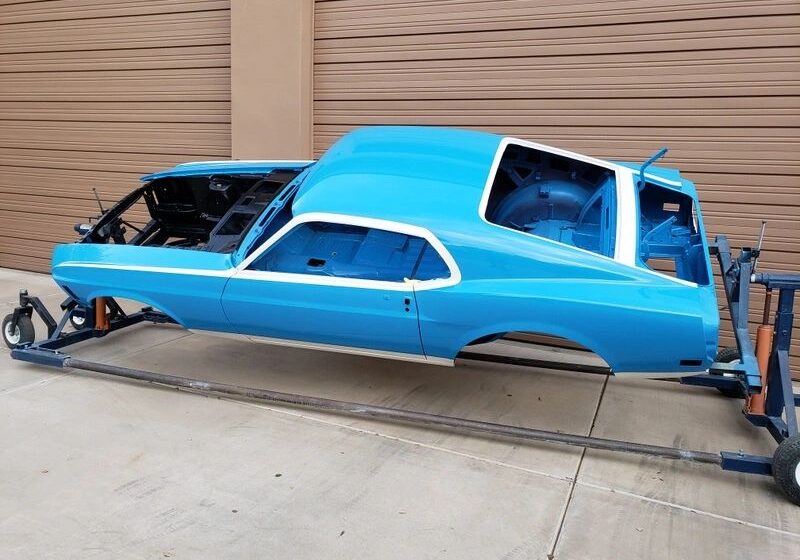 Blue car body on a rotisserie stand.