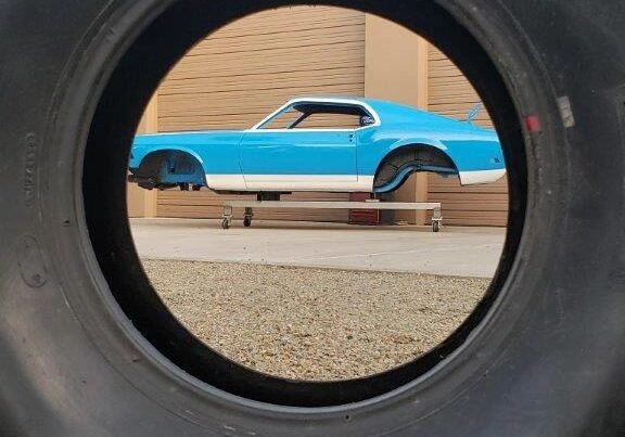 Blue car framed through large tire.