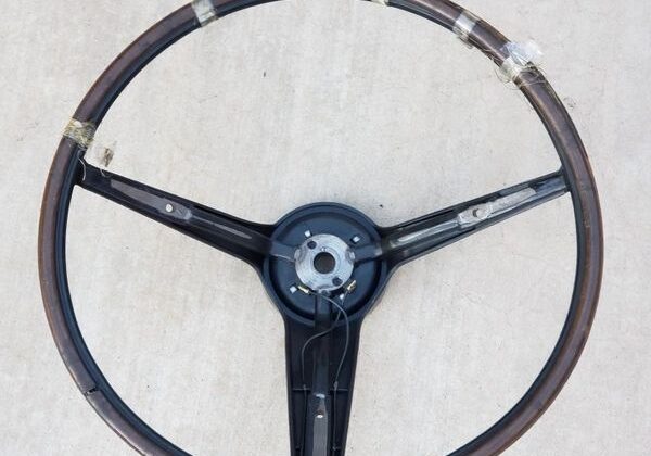 Vintage wooden car steering wheel on ground.