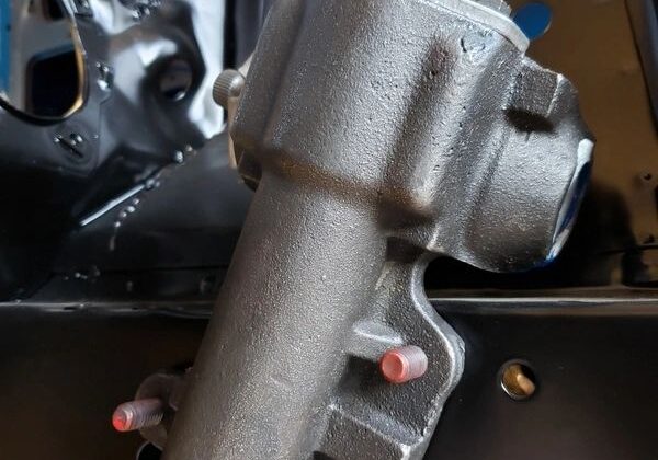 Metal steering box mounted on vehicle frame.