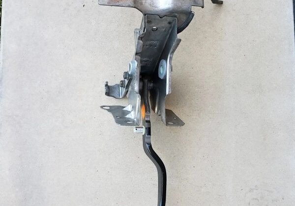 Metal car brake pedal assembly on concrete.