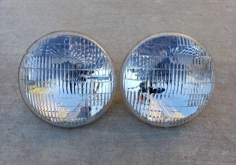 Two round car headlights on concrete surface.