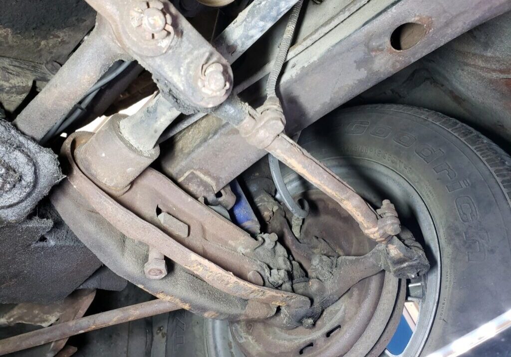 Rusty car suspension and tire close-up.