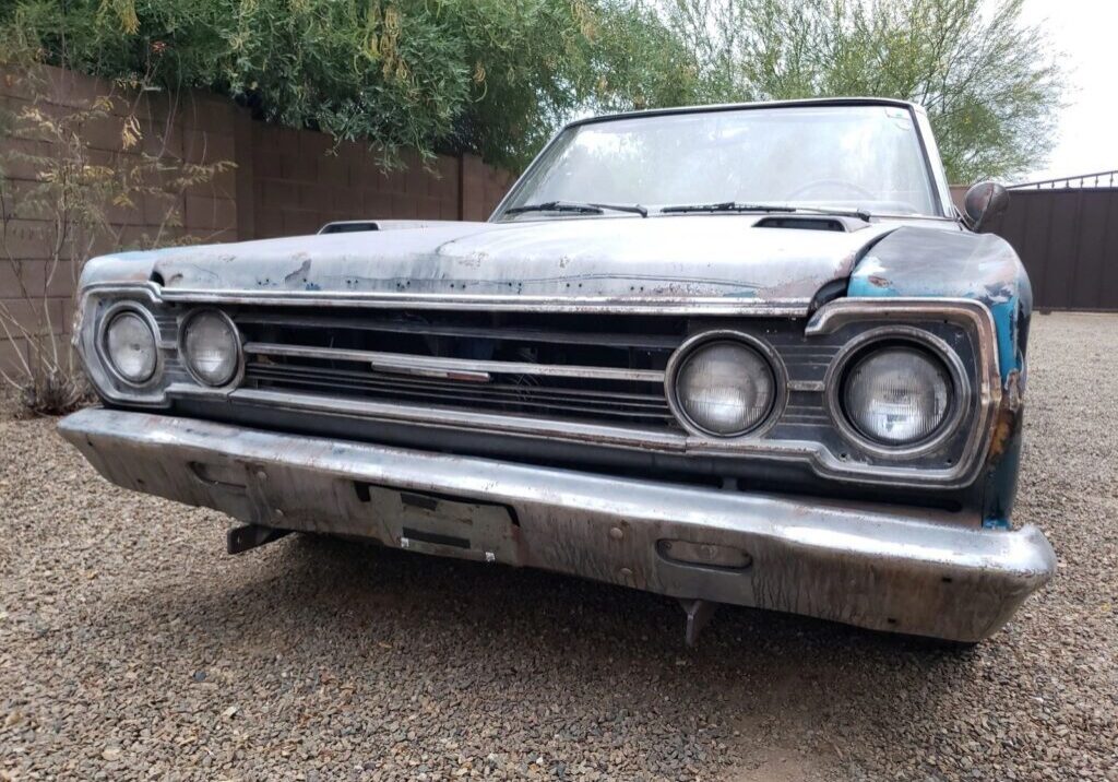Old rusty car with dual headlights front.