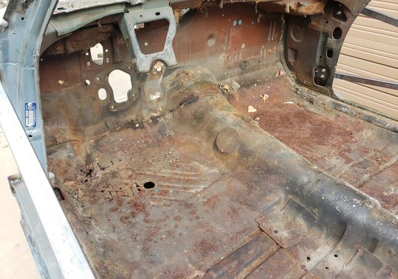 Rusty car interior with exposed metal floor.