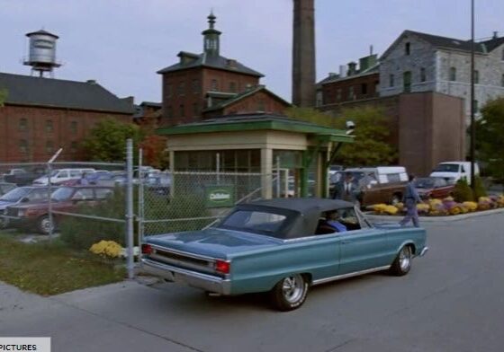 Blue car entering industrial complex entrance.