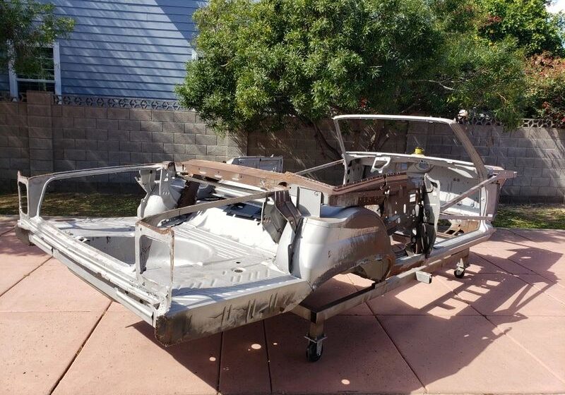 Car frame chassis on outdoor pavement.