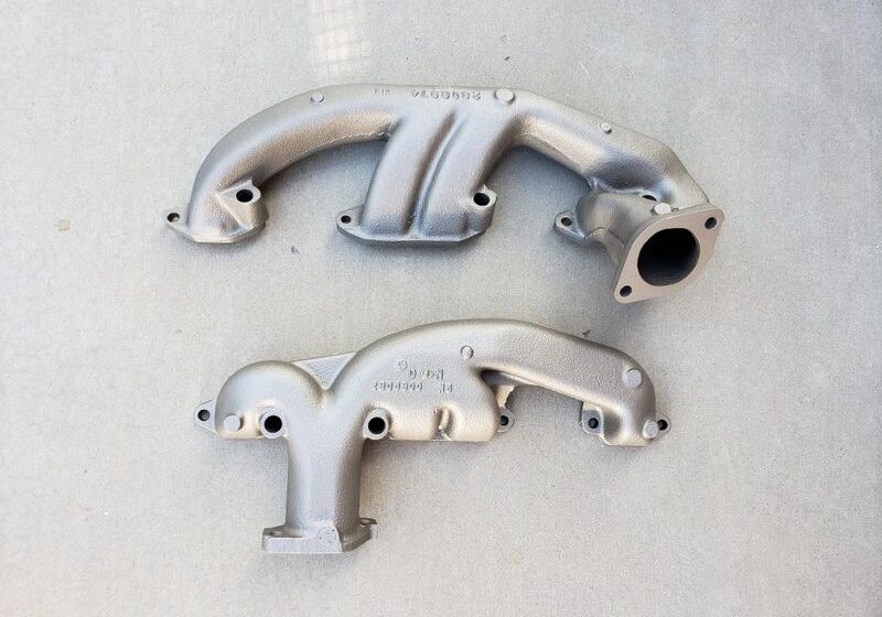 Two metal exhaust manifolds on concrete.