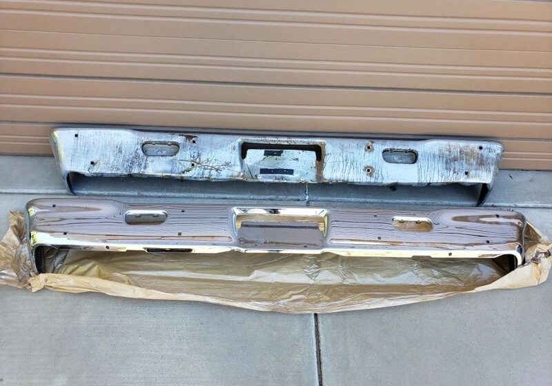 Two old car bumpers on concrete floor.