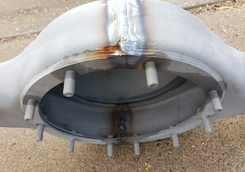 Metallic structure with bolts and weld marks.