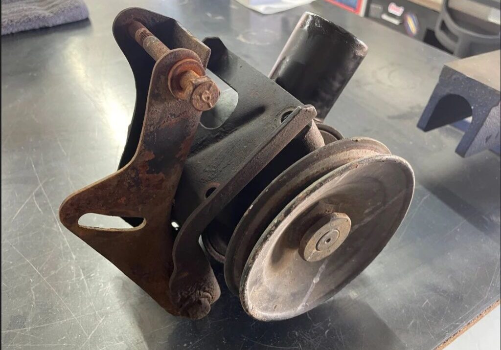 Rusty car engine pulley on a table.