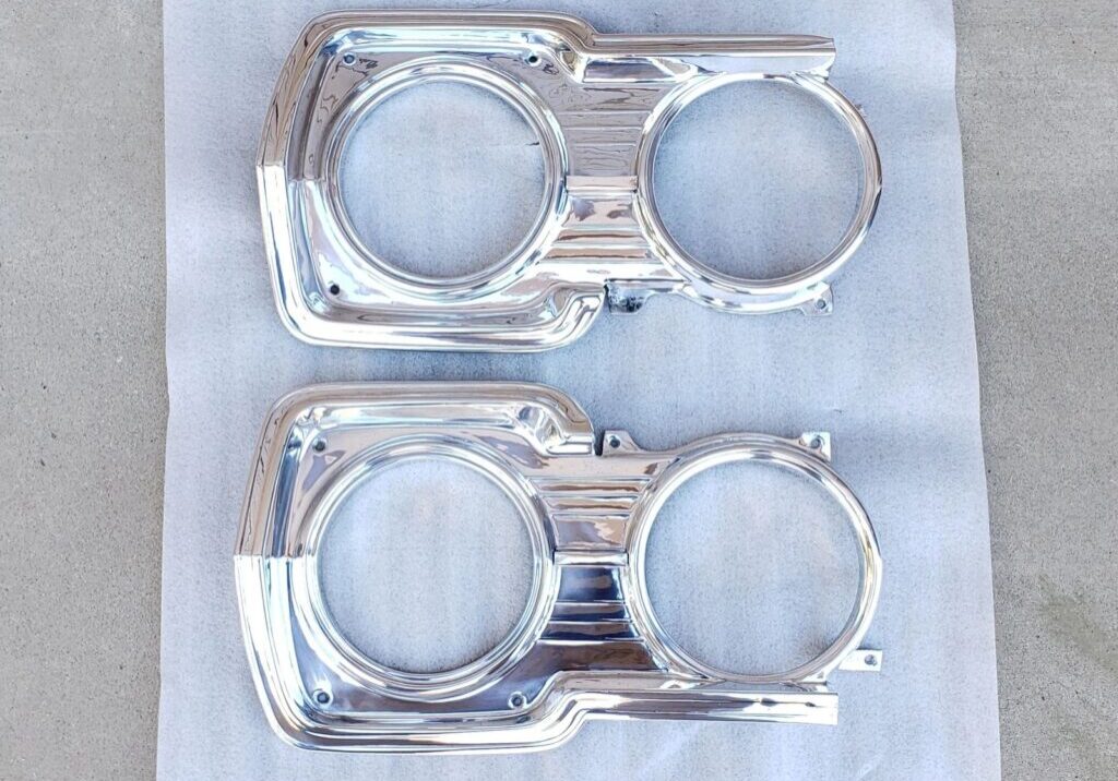 Chrome headlight bezels on white surface.