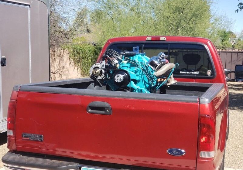 Red truck carrying a blue engine.
