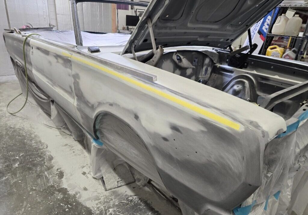 Classic car undergoing restoration in workshop.