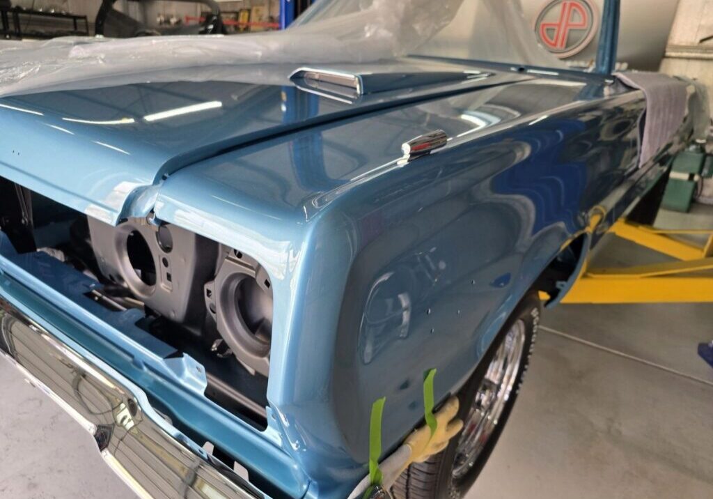 Classic blue car under restoration in garage.