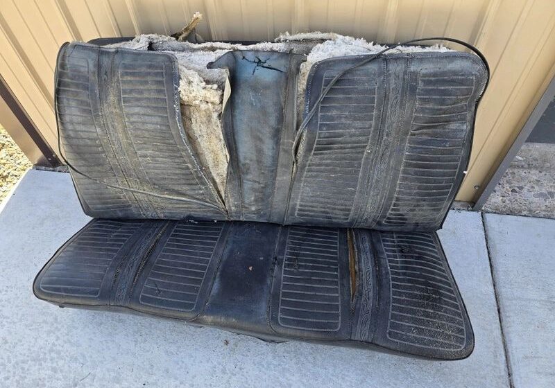 Worn-out car seat on concrete surface.