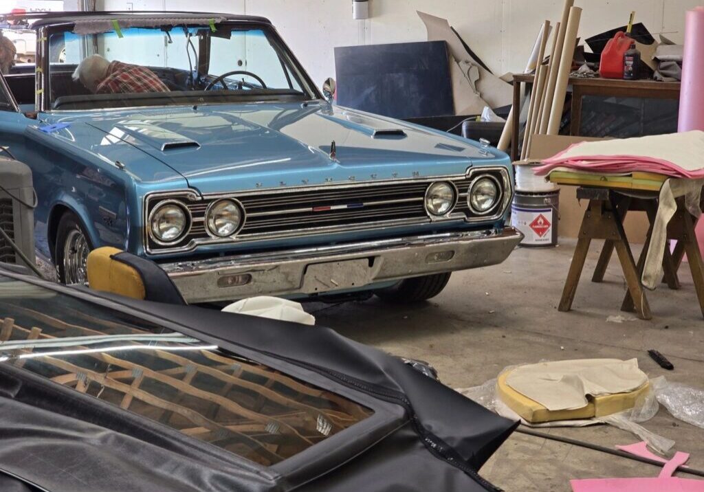 Blue vintage car in cluttered workshop.