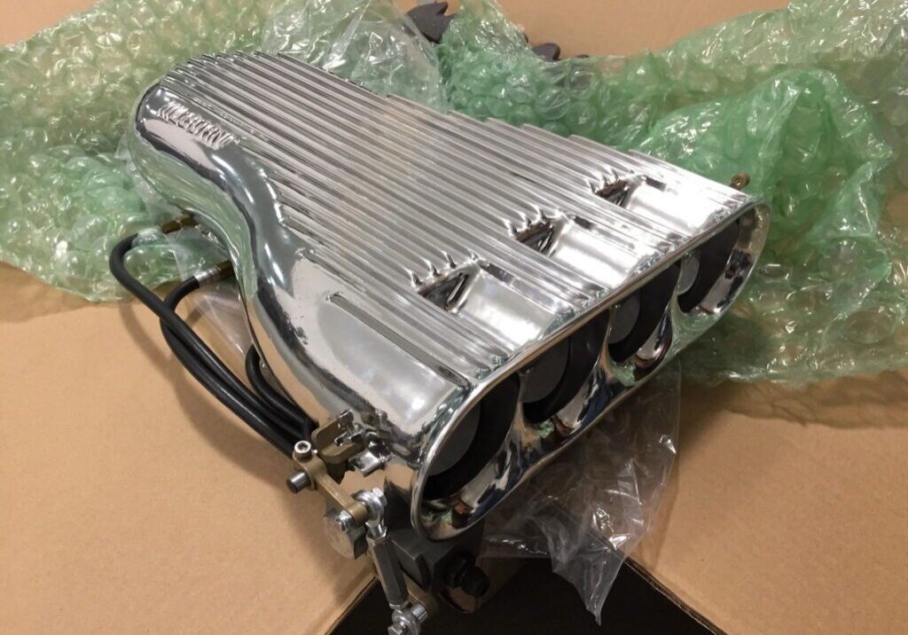 Chrome engine intake manifold on cardboard box.