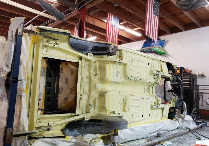 Car undercarriage being restored in workshop.