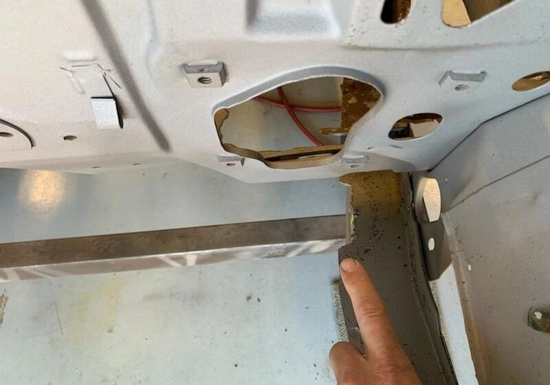 Finger pointing at car trunk repair area.