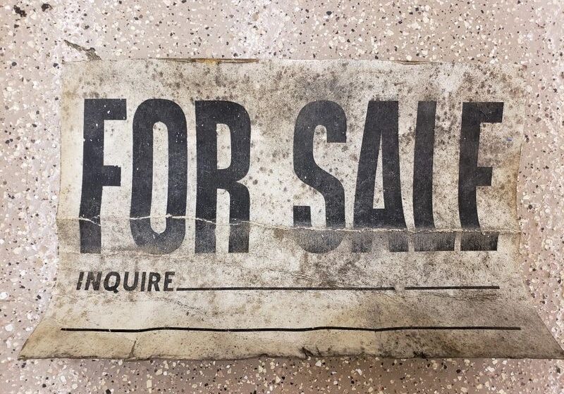 Worn "For Sale" sign on ground.