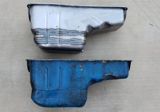 Two metal oil pans on concrete surface.