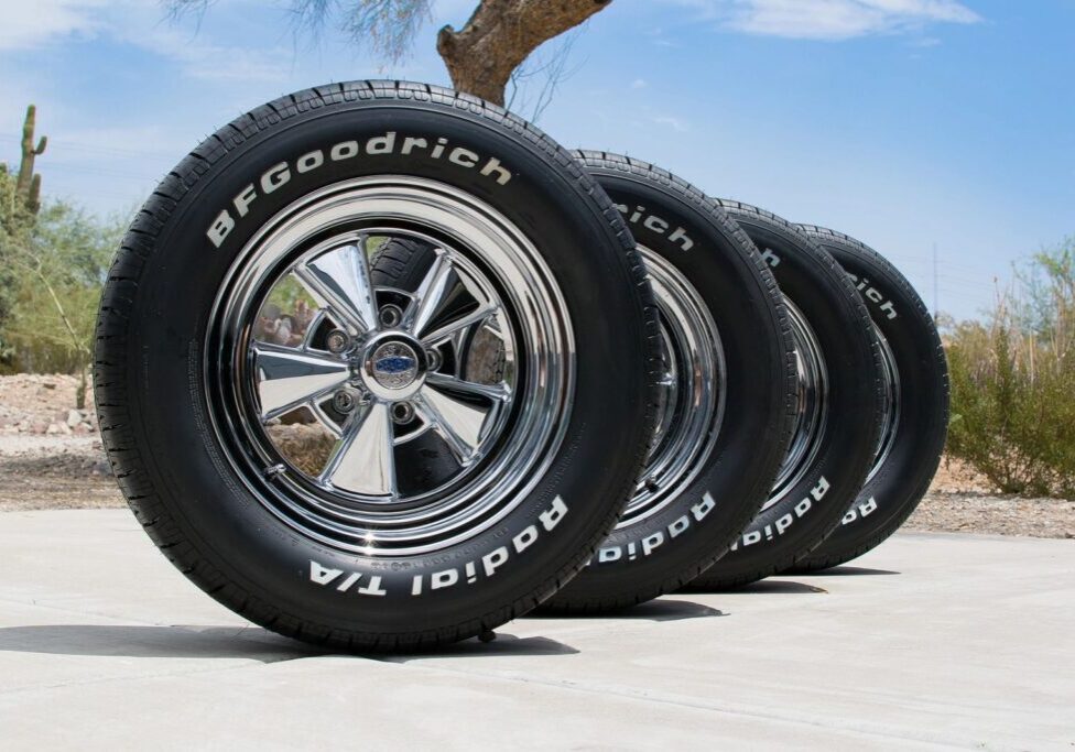 Four car tires stacked outdoors on pavement.