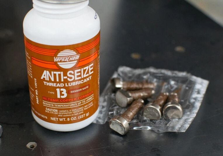 Anti-seize lubricant bottle with bolts nearby.