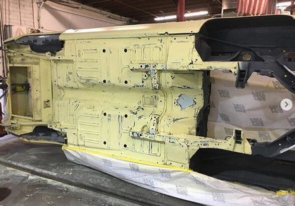 Car chassis undergoing restoration in workshop.