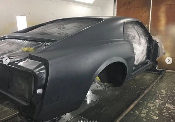 Car undergoing paint preparation in workshop.